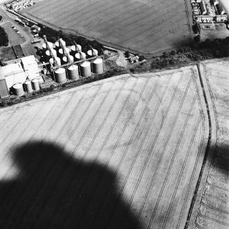 Wester Pencaitland, oblique aerial view, taken from the SW, centred on the cropmarks of a fort. Pencaitland Maltings is visible in the top left-hand corner of the photograph.