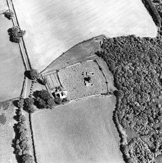 Oblique aerial view centred on the church, burial ground and burial enclosure with cropmarks of the field boundary adjacent, taken from the WSW.