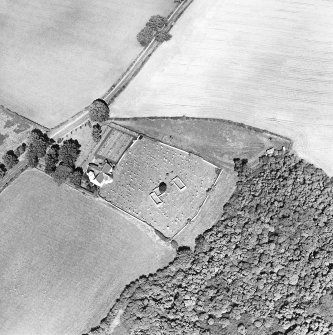 Oblique aerial view centred on the church, burial ground and burial enclosure with cropmarks of the field boundary adjacent, taken from the SW.