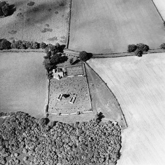 Oblique aerial view centred on the church, burial ground and burial enclosure with cropmarks of the field boundary adjacent, taken from the SSE.