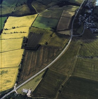 Oblique aerial view centred on the cropmarks of the Roman temporary camps and enclosure with the Roman fort and annexes adjacent, taken from the NE.