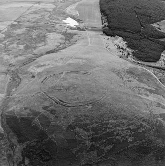 Oblique aerial view centred on the remains of the fort and standing stone, taken from the NNW.