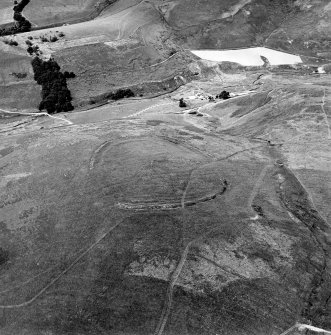 Oblique aerial view centred on the remains of the fort and standing stone, taken from the SE.