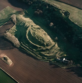 Oblique aerial view centred on the remains of the fort with farmsteading adjacent, taken from the WNW.
