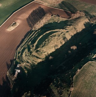 Oblique aerial view centred on the remains of the fort with farmsteading adjacent, taken from the SW.