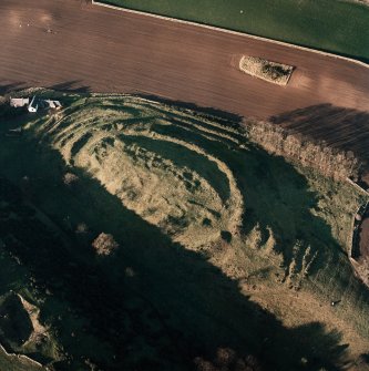 Oblique aerial view centred on the remains of the fort with farmsteading adjacent, taken from the SE.