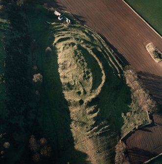 Oblique aerial view centred on the remains of the fort with farmsteading adjacent, taken from the ESE.