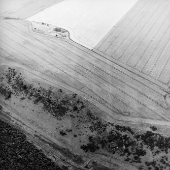 Oblique aerial view centred on the cropmarks of the forts, taken from the NW.