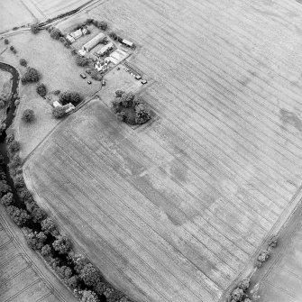 Oblique aerial view centred on the cropmarks with the burial-ground, the farmhouse and the watermill and kiln adjacent, taken from the ESE.