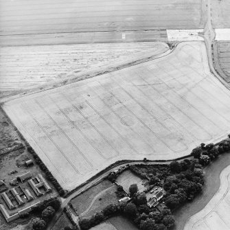 Oblique aerial view centred on the cropmarks of the airship sheds and adjacent circular features, the farmsteadings and dovecot, taken from the NNE.