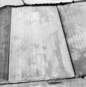 Oblique aerial view centred on the cropmarks of the ring-ditches and linear cropmarks with settlement adjacent, taken from the ENE.