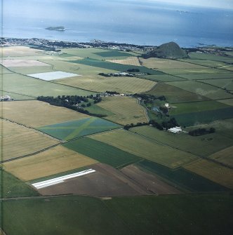 General oblique aerial view looking across Fenton tower-house, towards the remains of the fort and North Berwick beyond, taken from the SW.