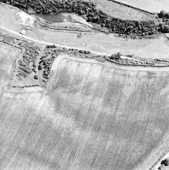 Oblique aerial view of Easter Broomhouse centred on the cropmark of a fort.  Taken from the NW.