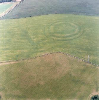 Oblique aerial view centred on the cropmarks of the fort with field boundaries and  cropmarks adjacent, taken from the SW.