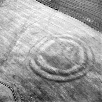Oblique aerial view centred on the cropmarks of the fort with field boundaries and  cropmarks adjacent, taken from the S.