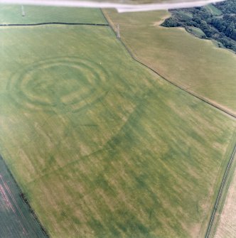 Oblique aerial view centred on the cropmarks of the field boundaries and cropmarks with fort adjacent, taken from the NNW.