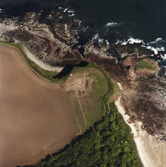 Oblique aerial view centred on the excavation of the chapel and cemetery with the remains of the laird's house adjacent, taken from the SSE.