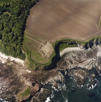 Oblique aerial view centred on the excavation of the chapel and cemetery with the remains of the laird¿s house adjacent, taken from the NE.