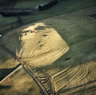 Oblique aerial view centred on the remains of rig, cairn and quarry, taken from the W.
