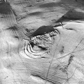 Oblique aerial view centred on the remains of the fort with rig and field banks adjacent, taken from the SW.