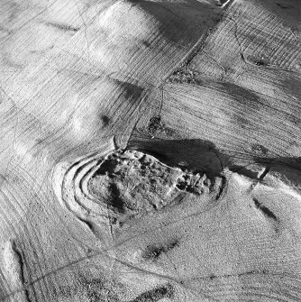 Oblique aerial view centred on the remains of the fort with rig and field banks adjacent, taken from the SSW.