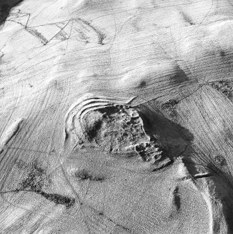 Oblique aerial view centred on the remains of the fort with rig and field banks adjacent, taken from the SSE.