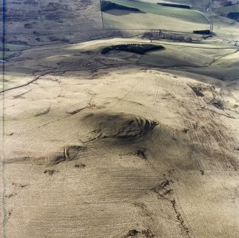 Oblique aerial view centred on the remains of the fort with the remains of the rig and field banks adjacent, taken from the NE.