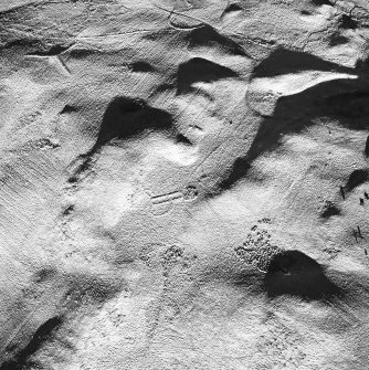 Oblique aerial view centred on the remains of the building and enclosures with rig adjacent, taken from the SW.