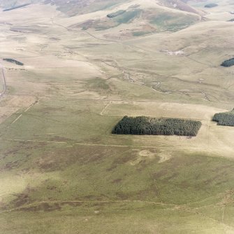 Pennymuir, oblique aerial view, taken from the WNW, centred on three Roman Temporary Camps, a linear earthwork and an area of rig. The course of 'Dere Street' is visible in the centre of the photograph.
