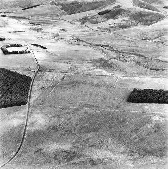 Pennymuir, oblique aerial view, taken from the WSW, centred Roman Temporary Camps, a linear earthwork and an area of rig. The course of 'Dere Street' is shown in the centre of the photograph.