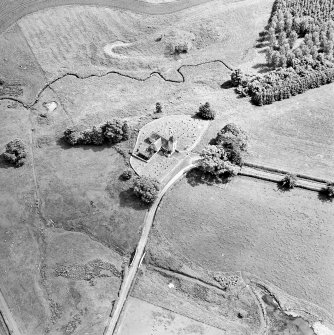 Oblique aerial view centred on the church and burial ground, taken from the NW.
