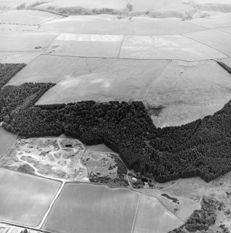 Oblique aerial view centred on the quarry and the remains of the earthwork with the remains of the settlement adjacent, taken from the NNE.