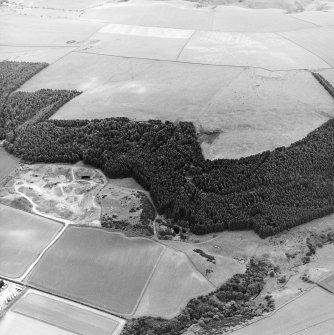 Oblique aerial view centred on the quarry and the remains of the earthwork with the remains of the settlement adjacent, taken from the NNE.