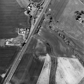 Thorntonloch, oblique aerial view, taken from the ESE, centred on the cropmarks of a fort and an enclosure, and showing the cropmark of a possible ring-ditch in the top left-hand corner of the photograph.