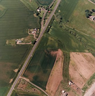 Thorntonloch, oblique aerial view, taken from the ESE, centred on the cropmarks of a fort and an enclosure, and showing the cropmark of a possible ring-ditch in the top left-hand corner of the photograph.