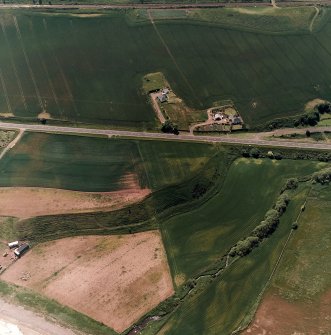 Thorntonloch, oblique aerial view, taken from the NE, centred on the cropmarks of a fort and an enclosure, and showing the cropmark of a possible ring-ditch in the top right-hand corner of the photograph.