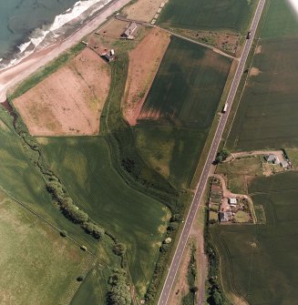 Thorntonloch, oblique aerial view, taken from the NW, centred on the cropmarks of a fort and an enclosure, and showing the remains of a Military Camp  in the top left-hand corner of the photograph.