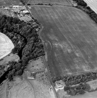 Oblique aerial view centred on the cropmarks of the fort with gate-lodge and walled garden adjacent, taken from the SSW.