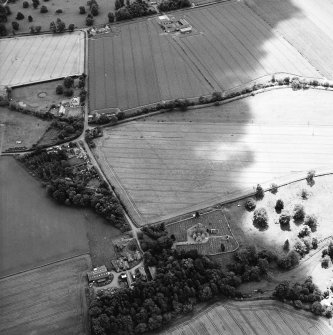 Oblique aerial view centred on the possible enclosures and linear cropmarks with the church, burial ground, manse, lodge, school, farmhouses, farmsteadings and cottages adjacent, taken from the NNE.