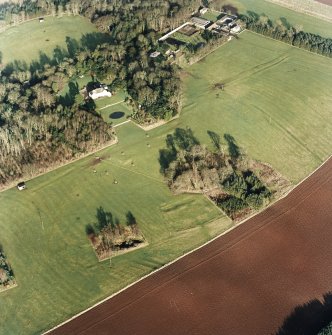 Oblique aerial view centred on the deserted medieval village, bastle, church and burial ground, with remains of the rig, possible enclosures, country house and walled garden adjacent, taken from the SW.