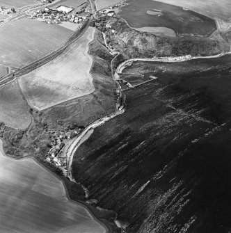 Oblique aerial view centred on the soilmarks, with the harbour adjacent, taken from the E.
