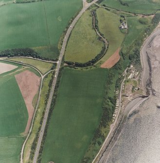 Innermessan, oblique aerial view, taken from the NNW, centred on the cropmarks of a possible enclosure, and showing the remains of Cairnryan Military Railway and associated camp and workshops in the right half of the photograph, and Innermessan Motte in the top right-hand corner.