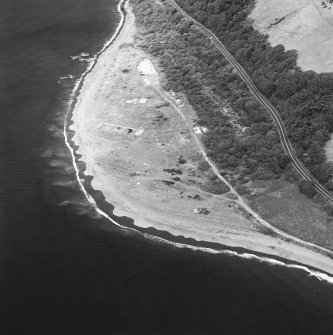 Oblique aerial view centred on the remains of the pile construction yard, scuttled ships, railway yard and railway, taken from the SSW.