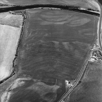 Ballantrae Bridge; Garleffin, oblique aerial view, taken from the SE, showing the cropmarks of a four poster stone-circle and a barrow in the bottom centre of the photograph. An area with pits and two possible souterrains, a round house, enclosures and linear cropmarks are visible in the centre, and field boundaries are shown in the upper half of the photograph.