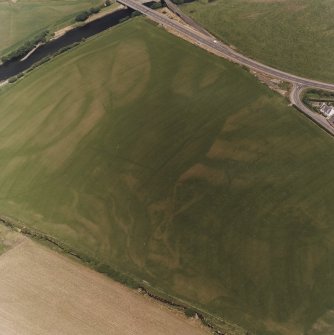 Ballantrae Bridge, oblique aerial view, taken from the SW, centred on the cropmarks of field boundaries and linear cropmarks, and on areas with pits. A possible souterrain and a round house are shown in the upper right-hand corner of the photograph, and cropmarks of possible enclosures and souterrain are shown in the bottom right-hand corner.
