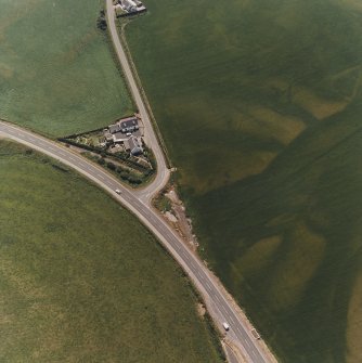 Ballantrae Bridge, oblique aerial view, taken from the N, centred on the cropmarks of a possible souterrain, a round house and pits. An area with pits is visible in the upper right-hand corner of the photograph.