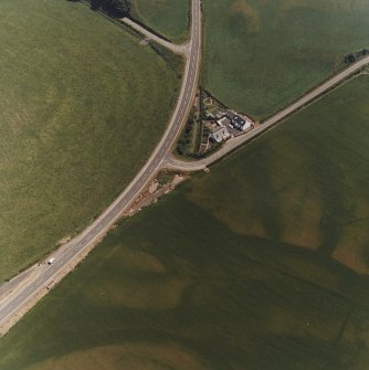 Ballantrae Bridge, oblique aerial view, taken from the NW, centred on the cropmarks of a possible souterrain, a round house and pits. An area with pits, field boundaries and linear cropmarks are visible in the bottom right-hand corner of the photograph.