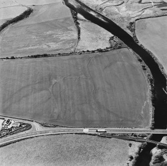 Oblique aerial view centred on the cropmarks of the field boundaries, linear cropmarks, pits, rig and cropmarks, taken from the NE.