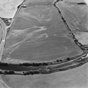 Oblique aerial view centred on the cropmarks of the field boundaries, linear cropmarks, pits, rig and cropmarks, taken from the NW.