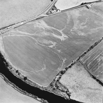 Oblique aerial view centred on the cropmarks of the field boundaries, linear cropmarks, pits, rig and cropmarks, taken from the W.